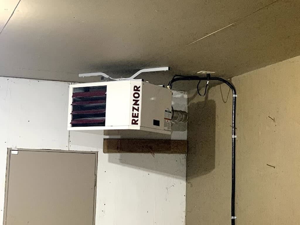 A wall mounted heater in a room with a ceiling.